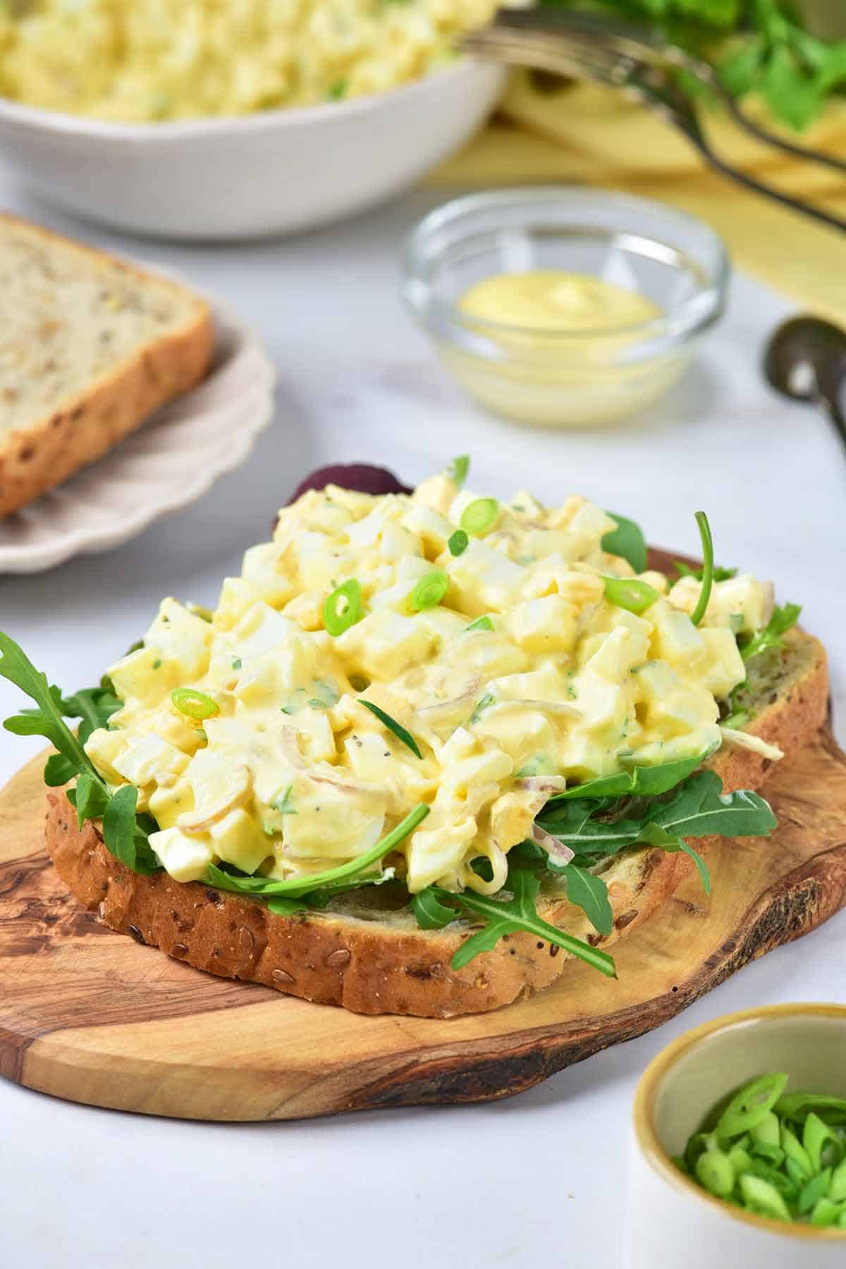 Egg salad served on a piece of toast with arugula on it