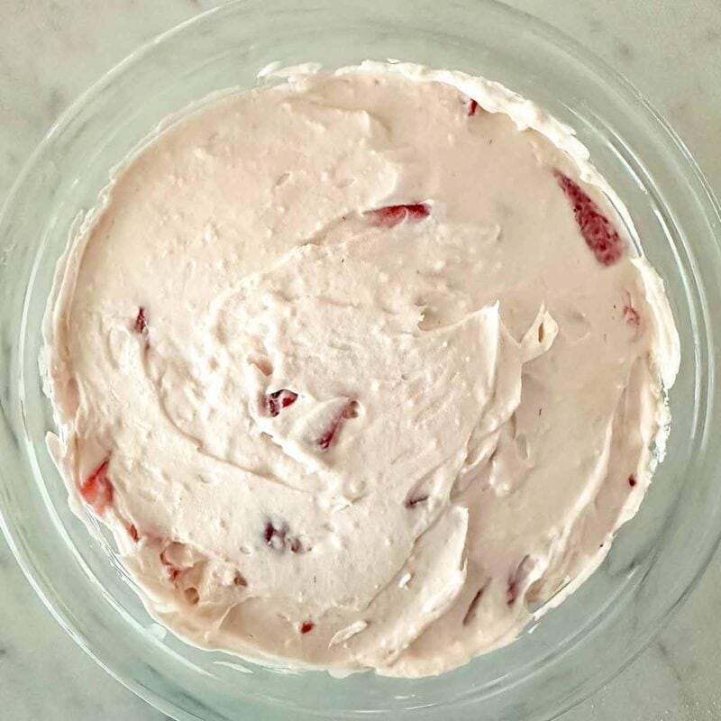 Strawberry cheesecake dip spread in a clear glass serving dish.