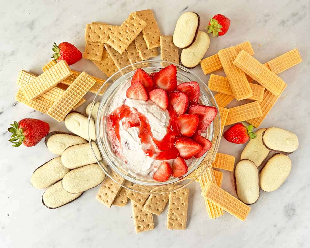 Cheesecake dip topped with fresh strawberries with cookies for dipping.