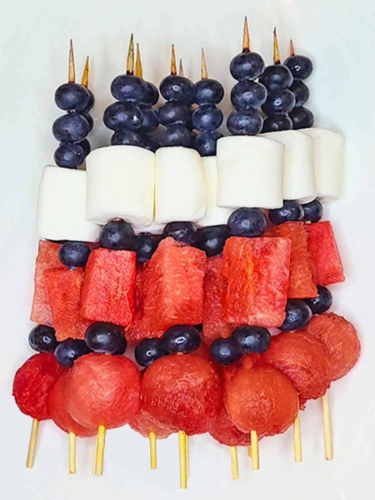 Patriotic red white and blue fruit skewers on a white background.