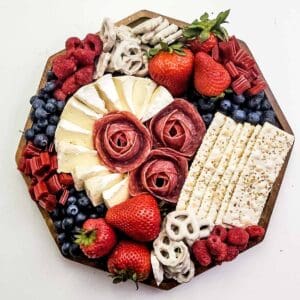 A charcuterie board filled with red, white, and blue foods like crackers, cheeses, and berries.