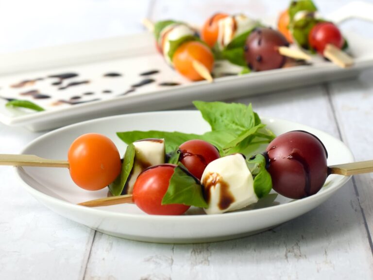 A plate of skewers with tomatoes and cheese.