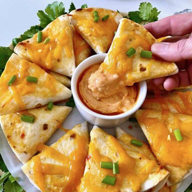 Dipping quesadillas in a bowl of sauce.