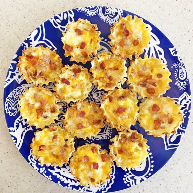 Bacon and cheese mini quiches on a blue serving plate.