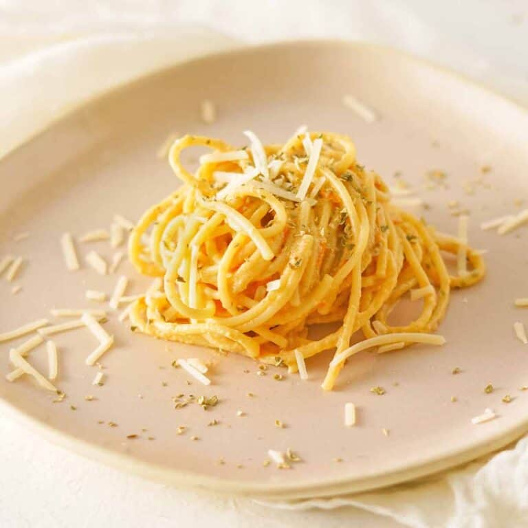A serving of burrata pasta on a beige ceramic plate.