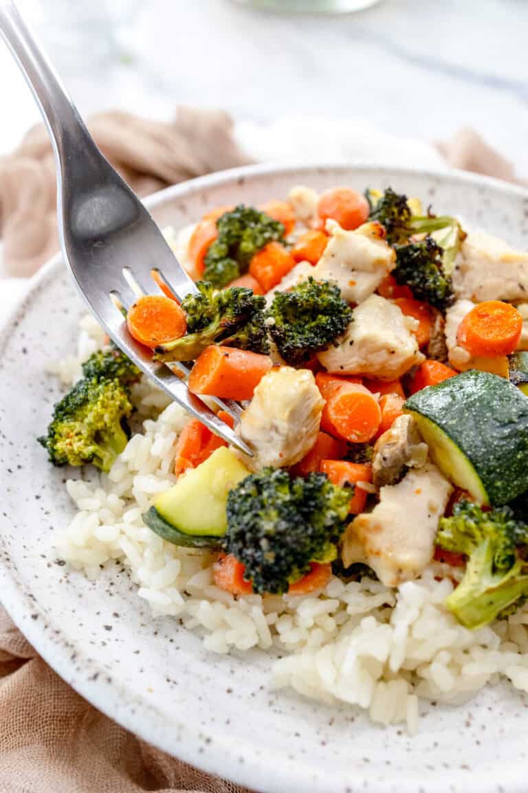 A white plate topped with chicken and vegetables over rice.