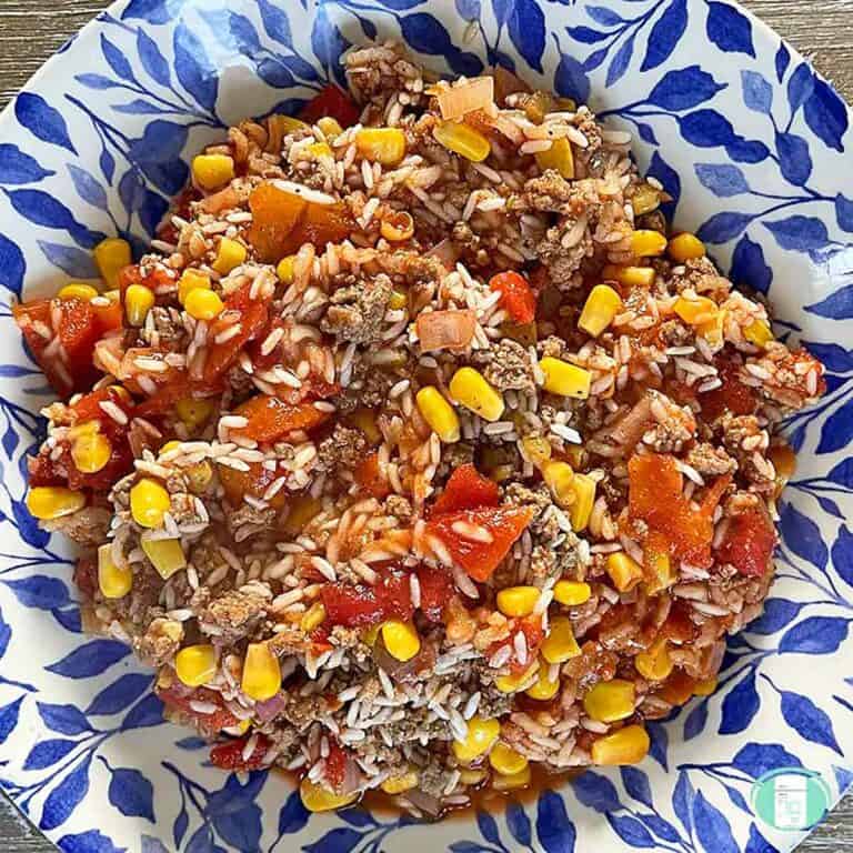 Green chile with rice and black beans on a blue and white plate.