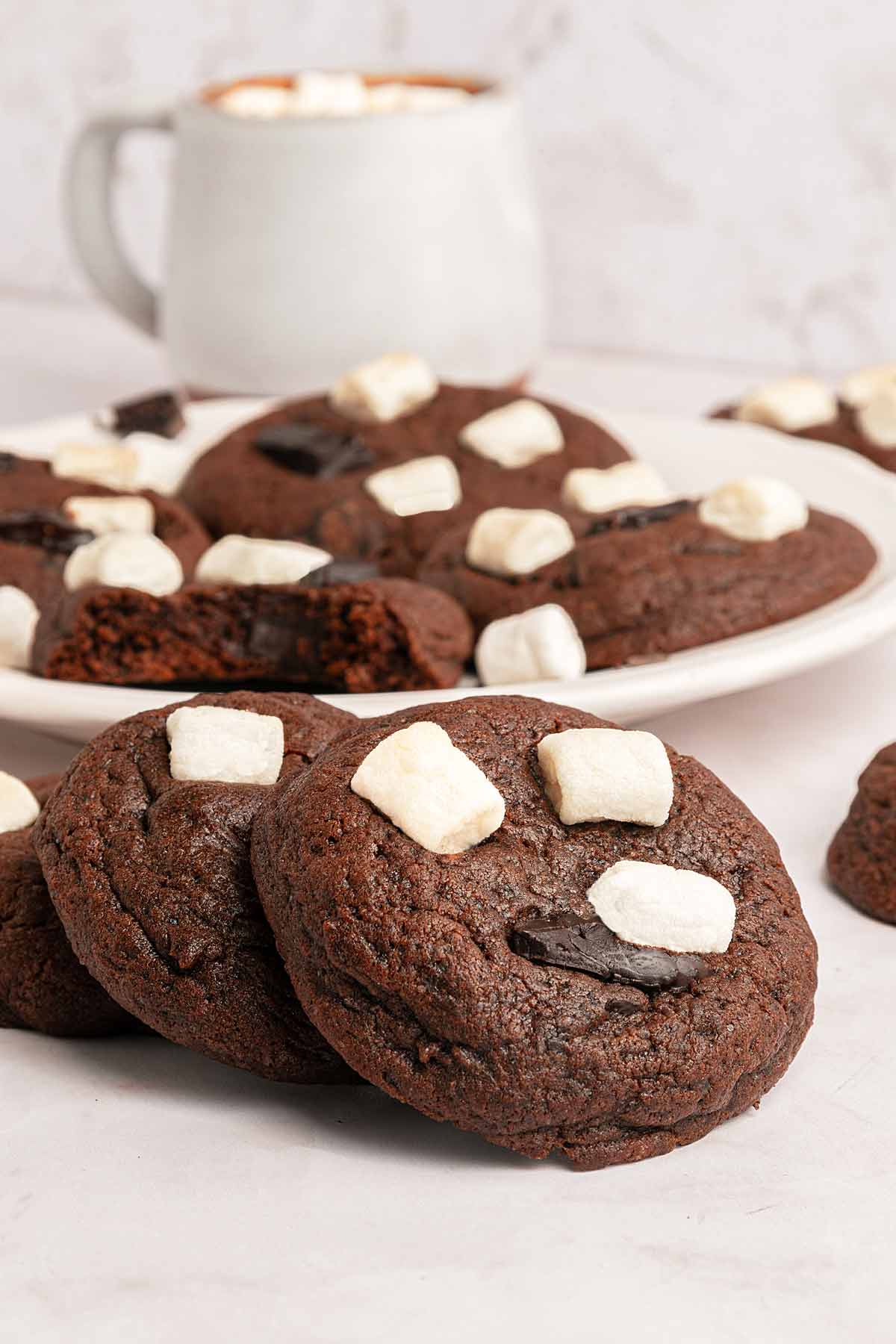 Marshmallow Hot Chocolate Cookies with a cup of cocoa in the background.