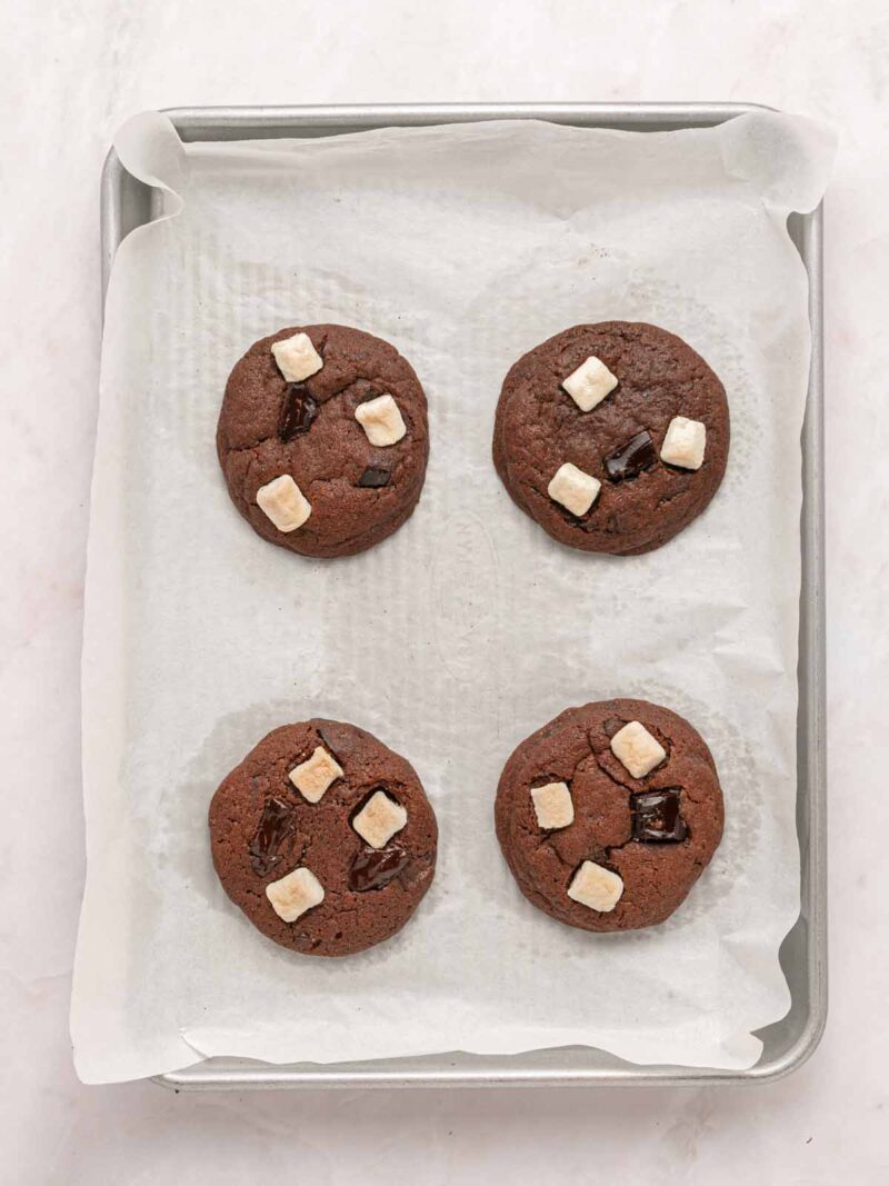 Four freshly baked hot chocolate cookies on a baking sheet.
