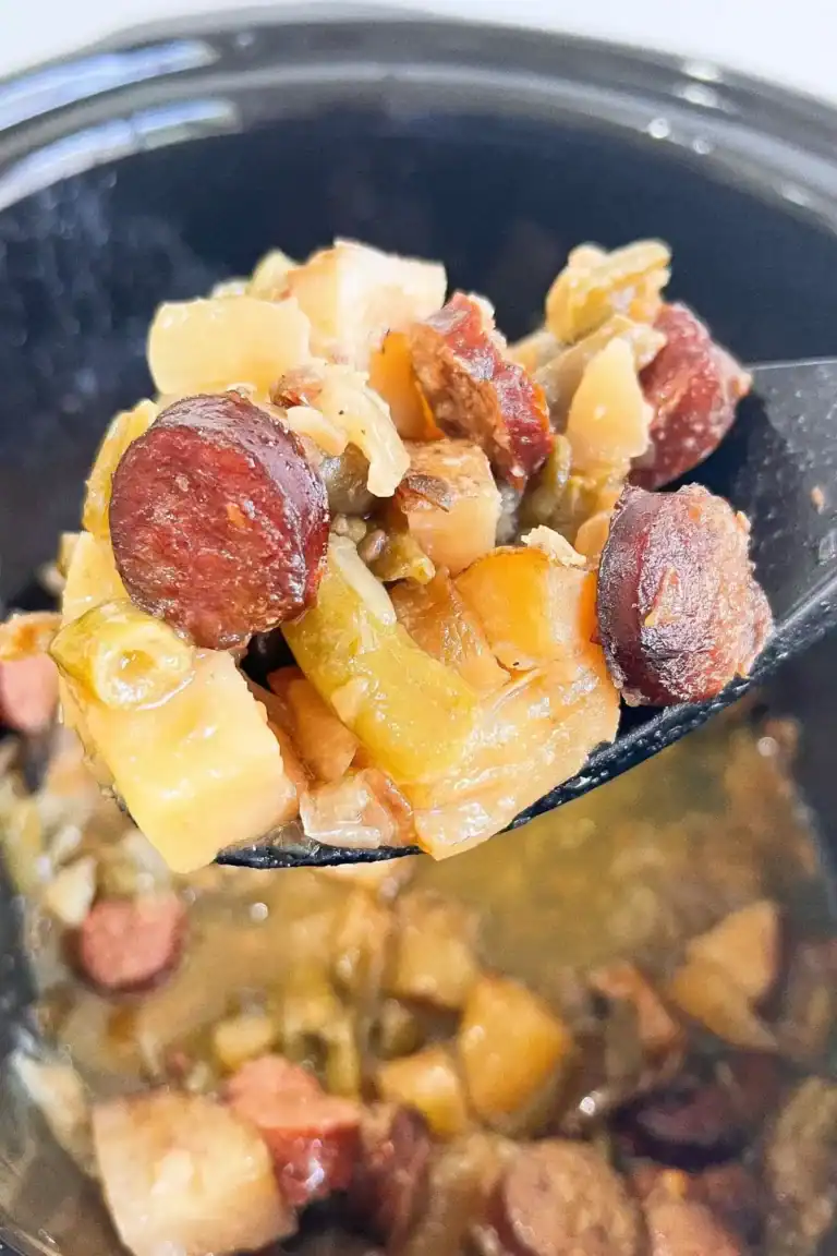 Black slow cooker full of Cajun swamp potatoes.