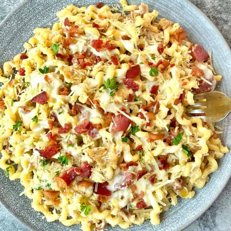 A dinner plate topped with chicken bacon parmesan pasta.