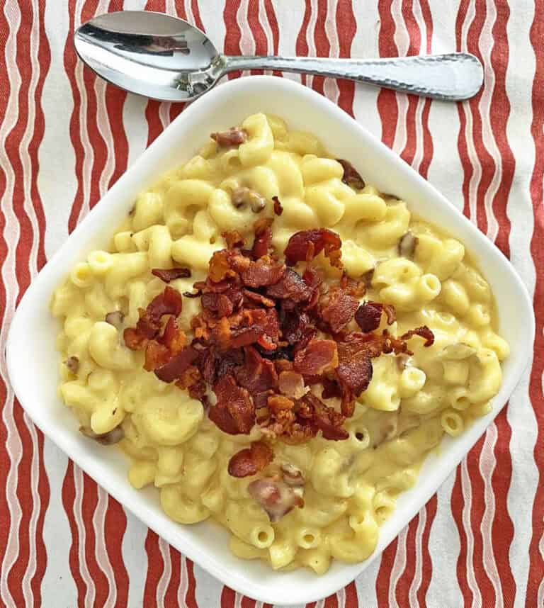 A bowl of bacon macaroni and cheese with a spoon.