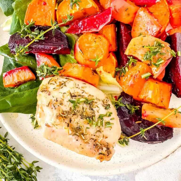 Fresh roasted chicken served with colorful roasted root vegetables and herbs.