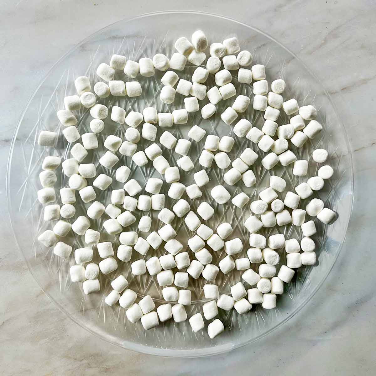 Mini marshmallows spread on a clear platter to dry.