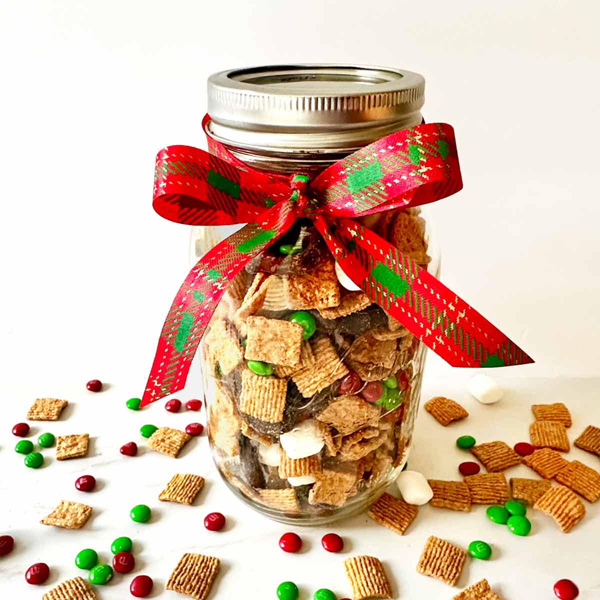 A glass Ball jar filled with homemade S mores snack mix and tied with a ribbon for a food gift.
