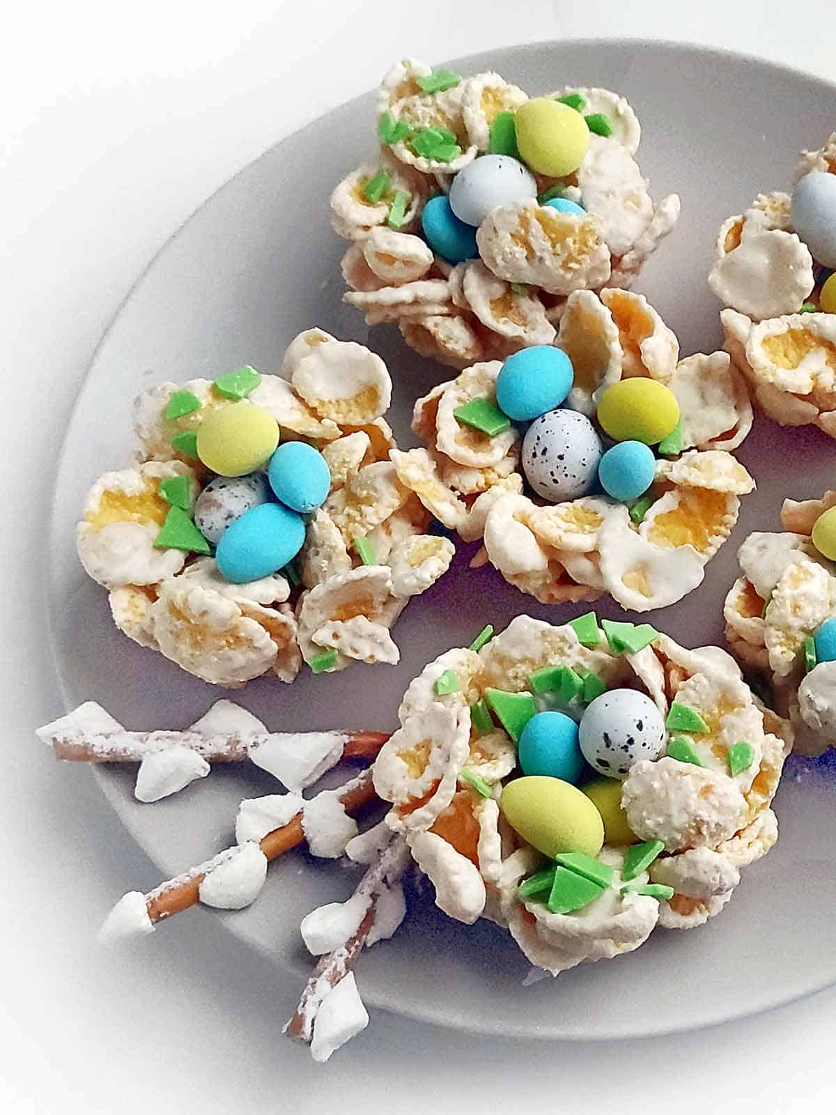 Six Easter birds nest cookies topped with mini chocolate eggs on a serving plate.