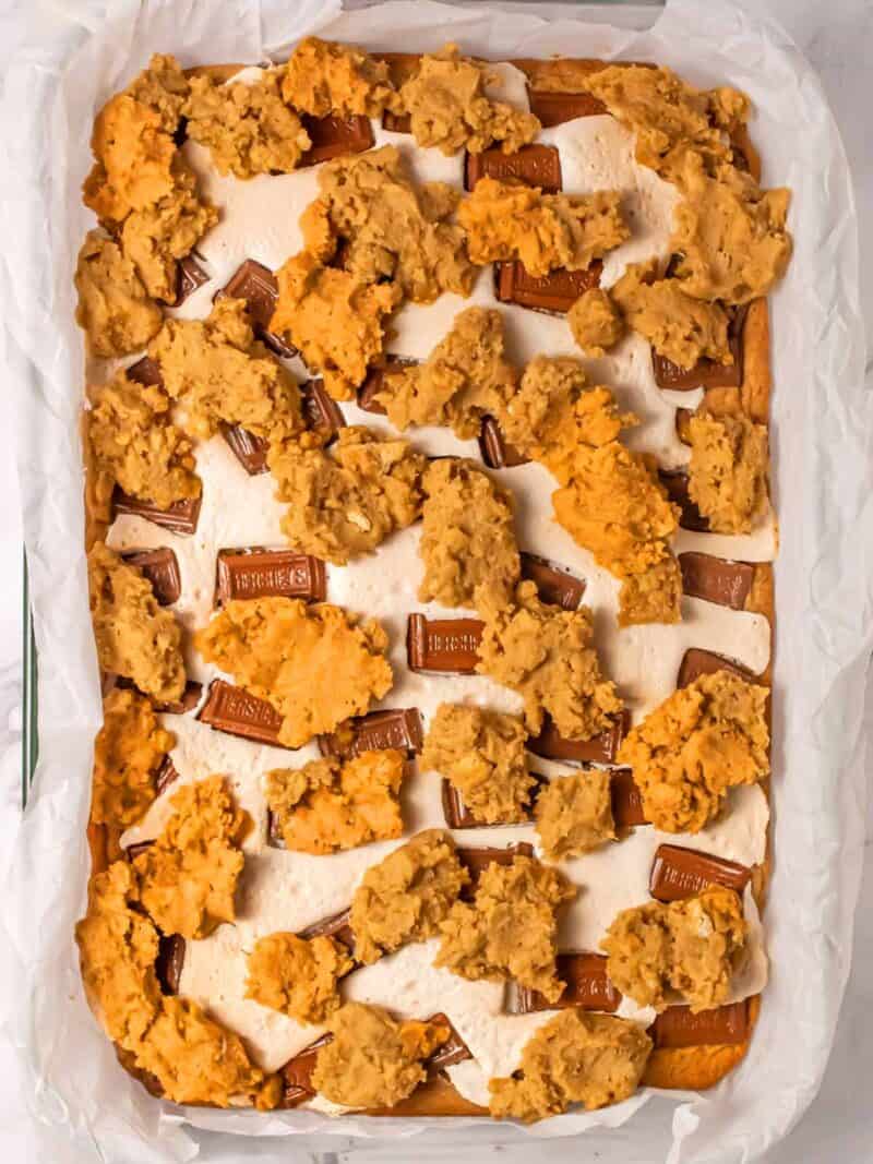 Unbaked s'mores bars in a parchment lined baking pan.