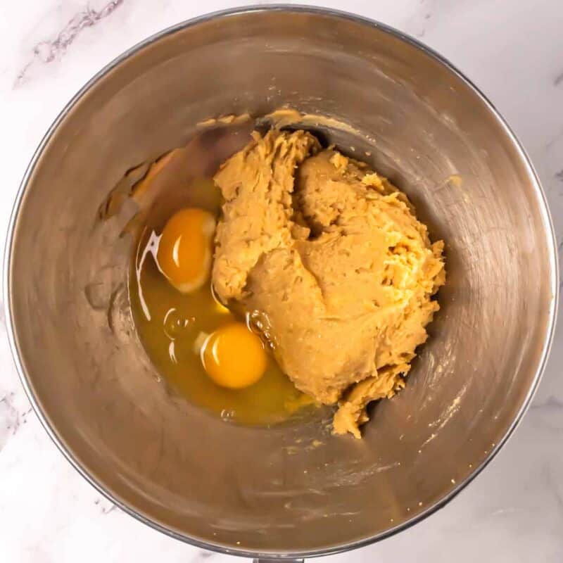 Making cookie dough with eggs in a stainless steel mixing bowl.