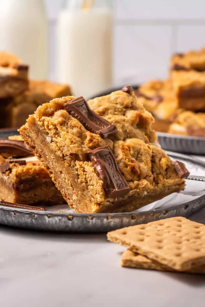 Smores bars on a plate with graham crackers and a glass of milk.