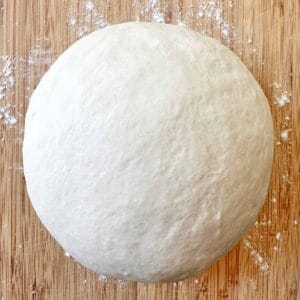 Ball of pizza dough on a floured work surface.