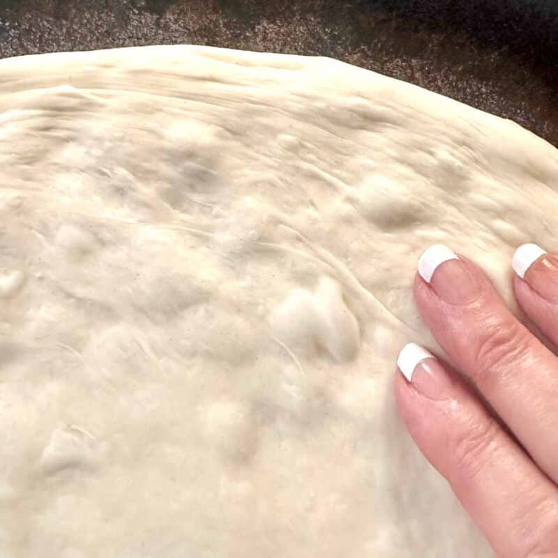 Pressing pizza dough in the round pan.