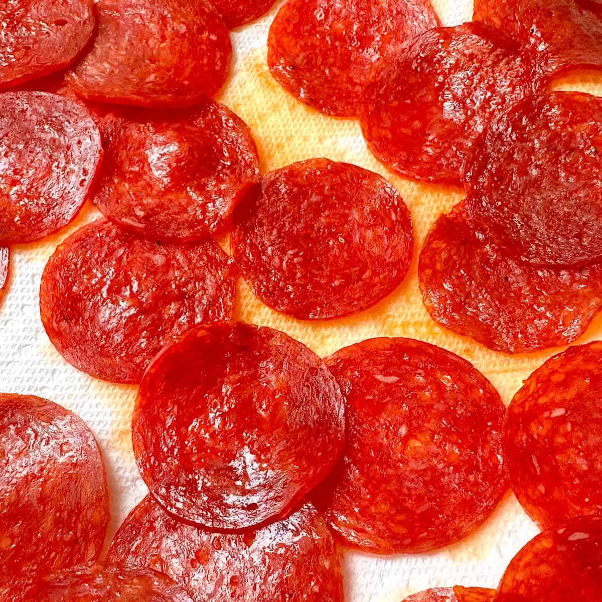 Pepperoni slices on paper towels after being heated in the microwave to remove excess grease.