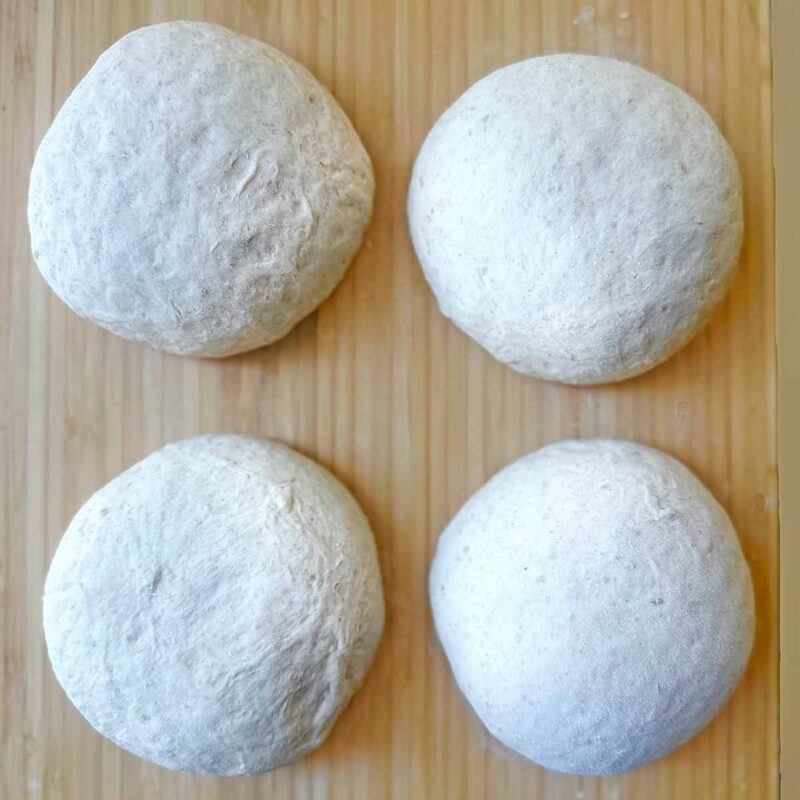 Spelt pizza dough shaped in four rounds.