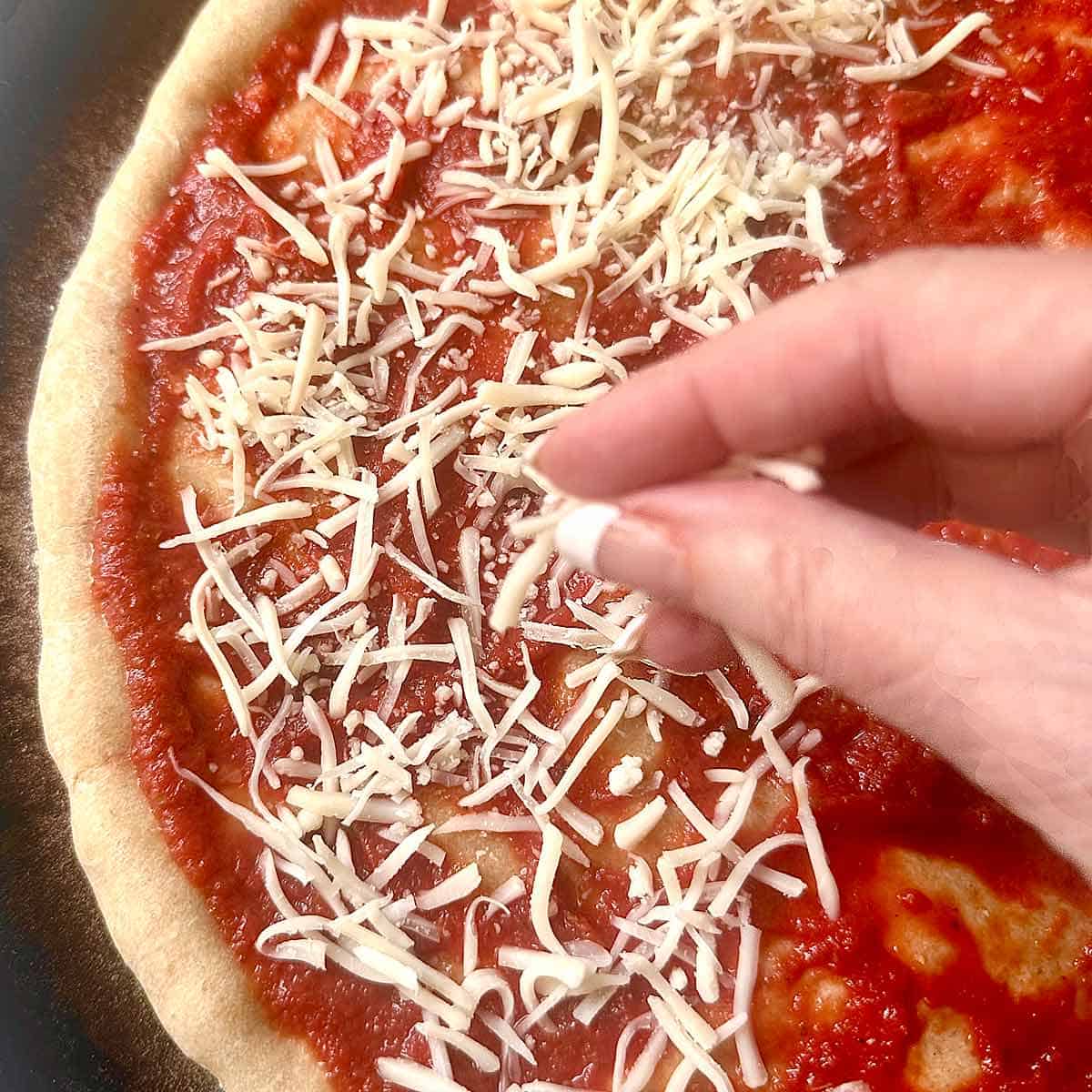 Sprinkling cheese on a homemade pizza.