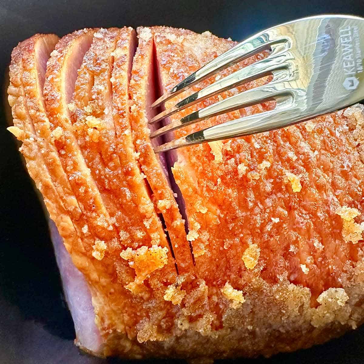 Using a fork to separate slices of a honey baked spiral ham.